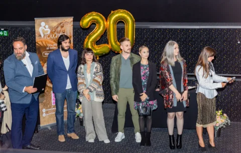 Echipa organizatoare pe scenă la gala aniversară de 20 de ani, cu baloane aurii