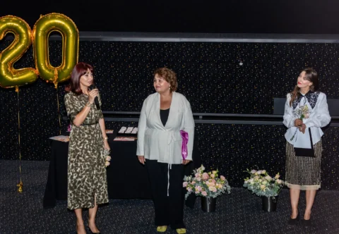 Discurs pe scenă la gala aniversară, cu buchete de flori în față
