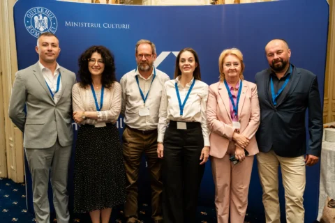 Fotografie de grup cu organizatorii conferinței, în fața panoului Ministerului Culturii