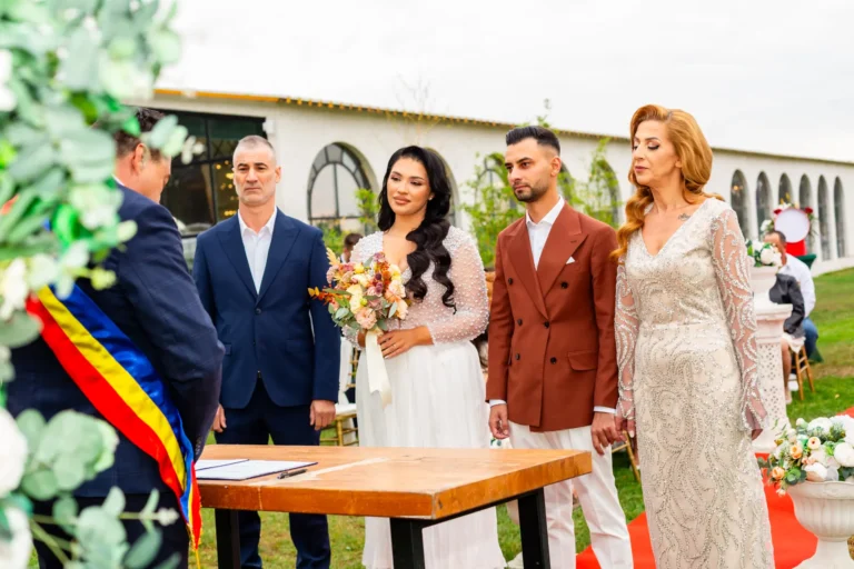 Ofițerul de stare civilă cu eșarfa tricoloră oficiază cununia în aer liber, alături de miri și nași
