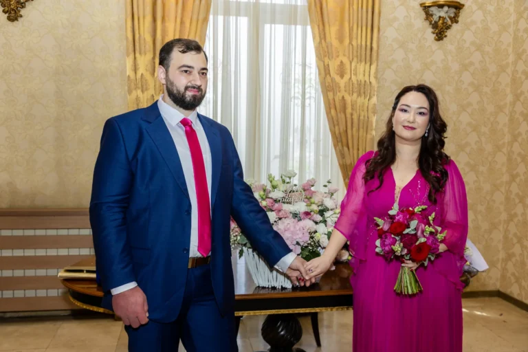 Mirii se țin de mână în sala stării civile, lângă masa cu flori