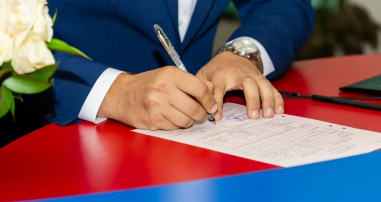 Detaliu: mâna mirelui semnând actul de căsătorie la starea civilă