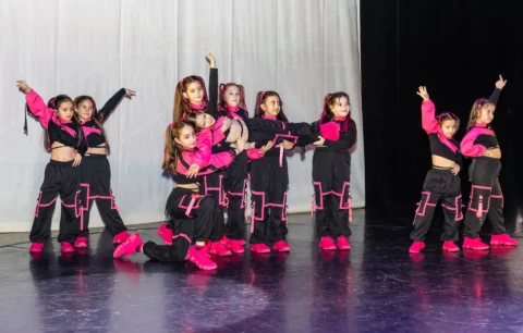 Grup de dans modern în costume negre cu roz, pe scenă
