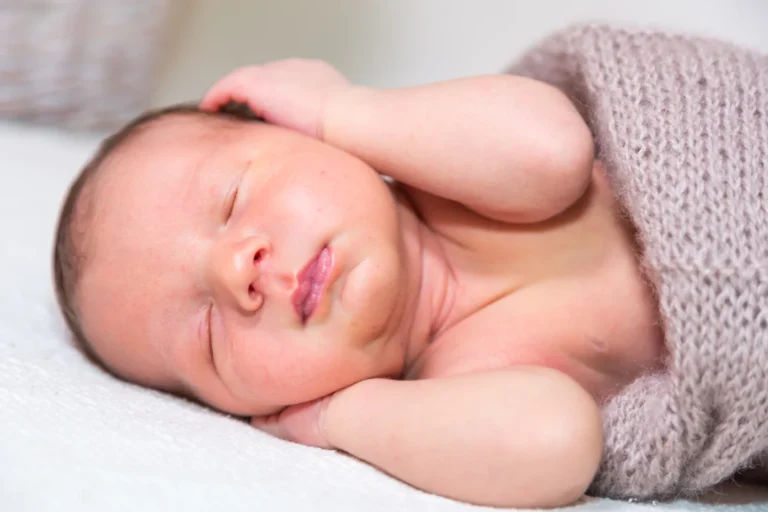 Bebeluș dormind cu mânuțele sub obraz, la ședința foto newborn