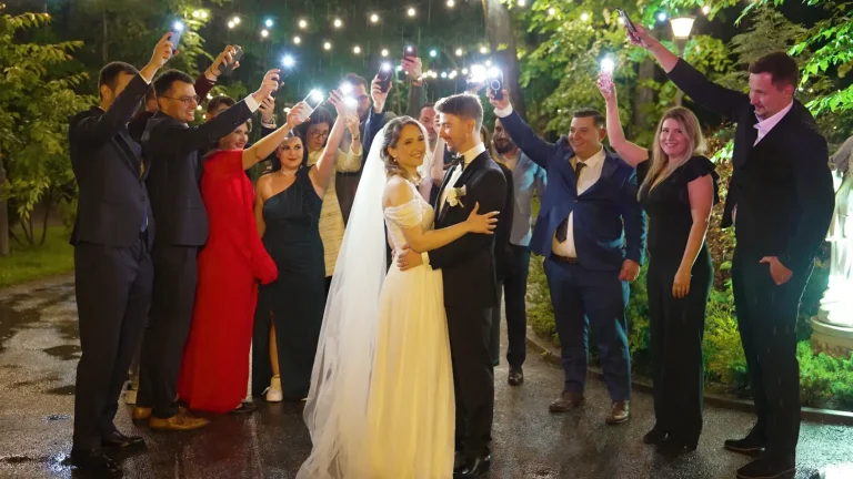 Mirii înconjurați de invitați cu lanternele telefoanelor aprinse, noaptea