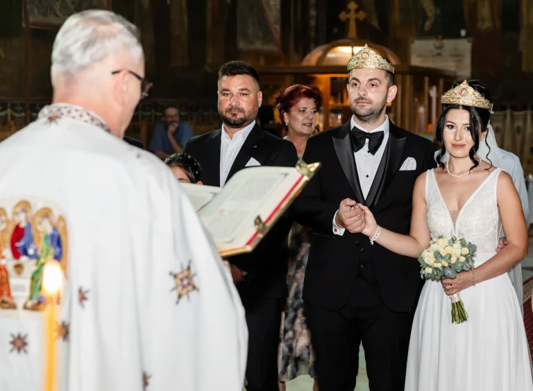 Preotul citește slujba cununiei, cu mirii și nașii în biserică