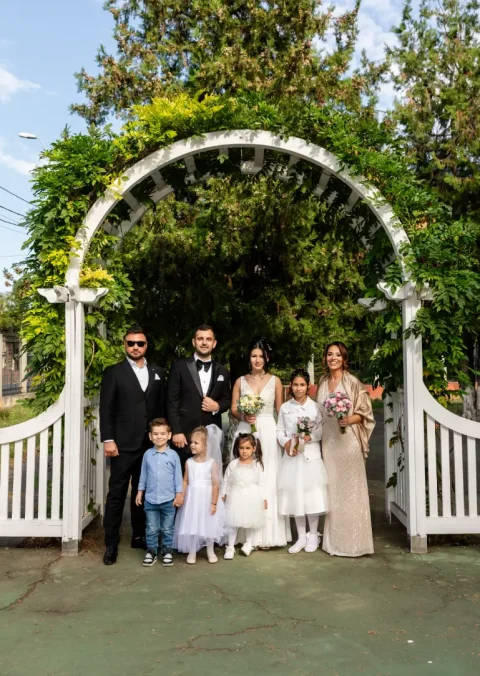 Mirii cu familia la o poartă albă, în grădină