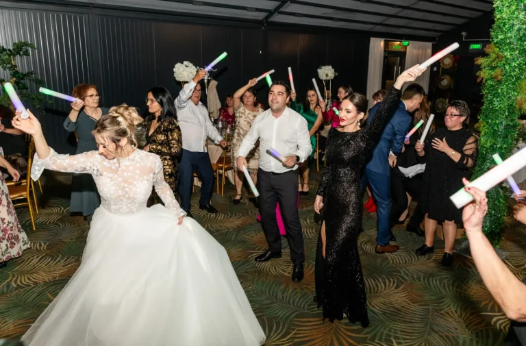 Mireasa dansând cu invitați care țin bețe luminoase