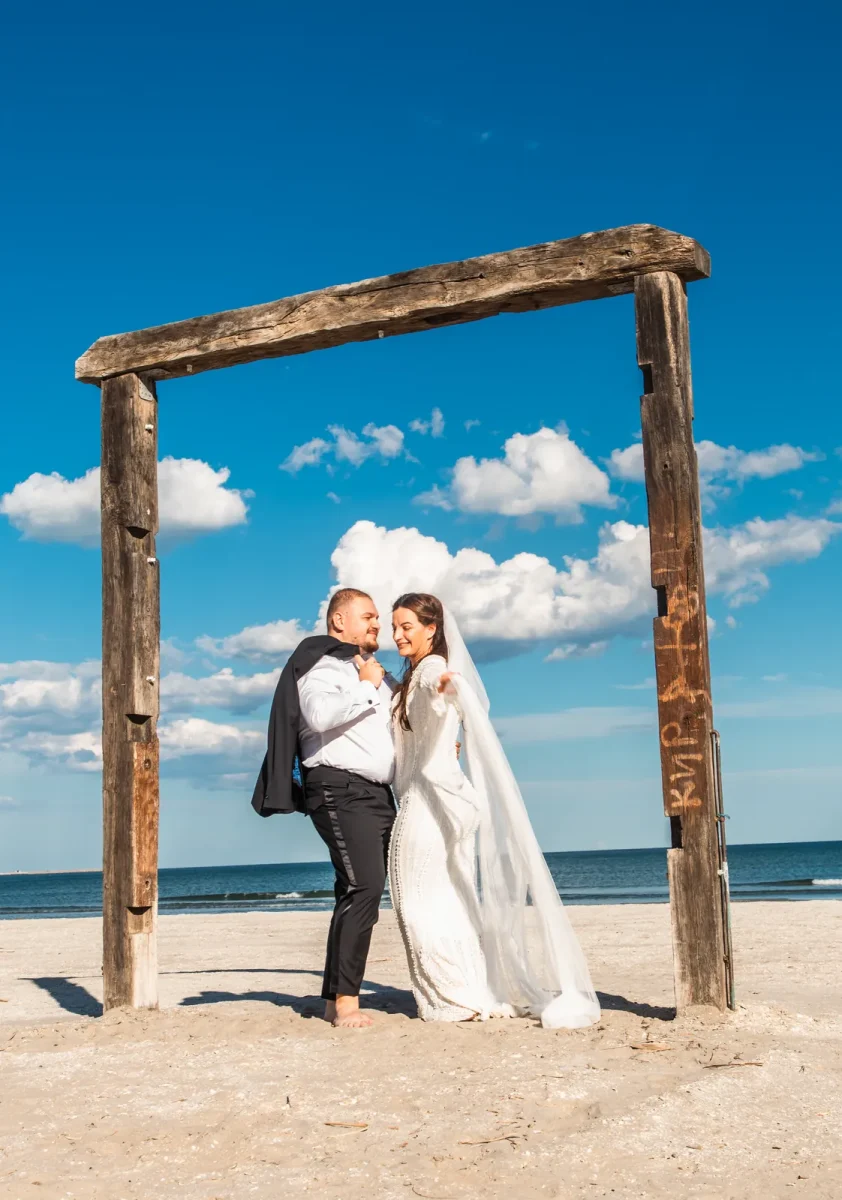 Mirii sub un portal de lemn pe plajă, la ședința trash the dress